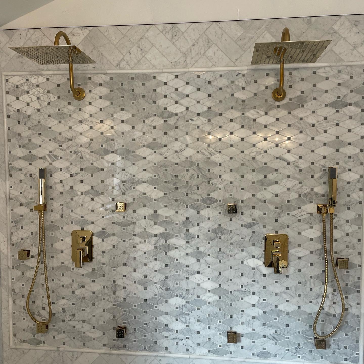 Double rainfall shower system with gold hardware on marble tile installed by HSC Plumbing