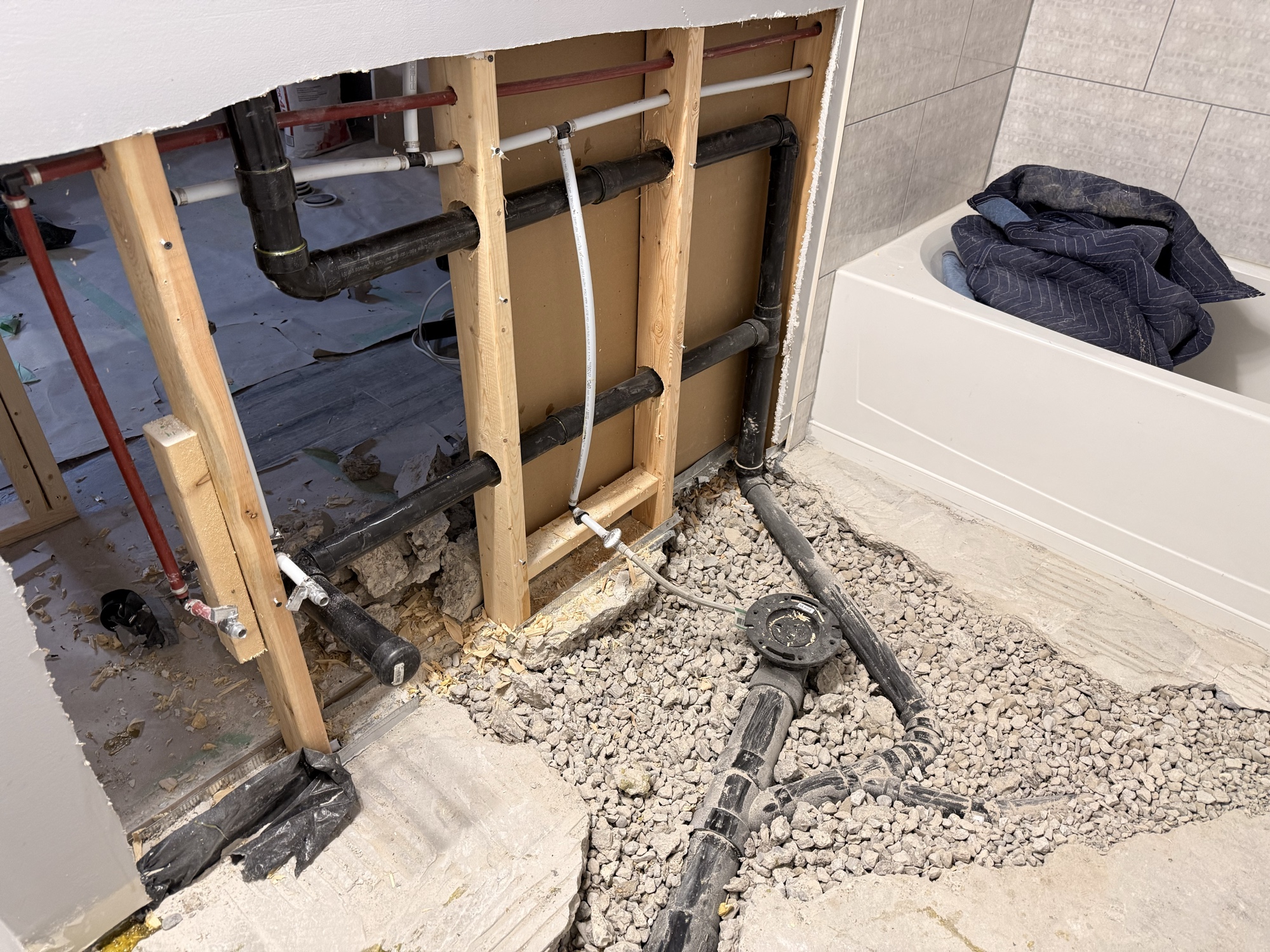 Drain rough-in with ABS waste pipes through wall framing in bathroom renovation